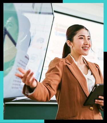 A professional Asian business woman presents data on screens in a board meeting room