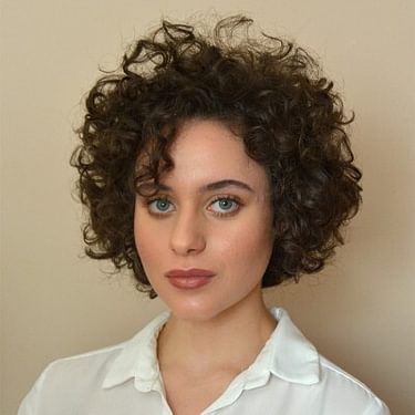 Portrait photo of Simone Wisniewski. She has short curly hair and is wearing a white-collar shirt.