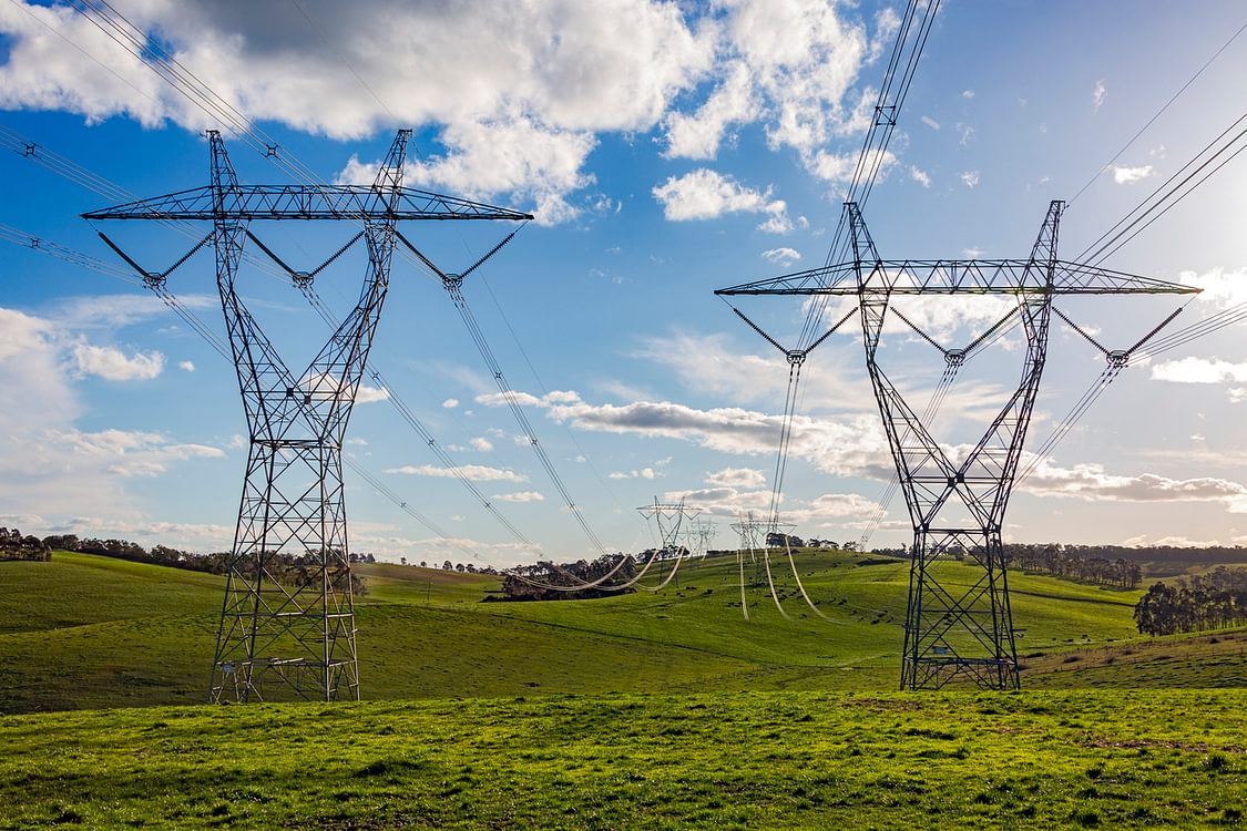 Electrical power pylons crossing green farmland